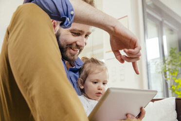 Vater zeigt seiner kleinen Tochter etwas auf einem digitalen Tablet - MFF002888