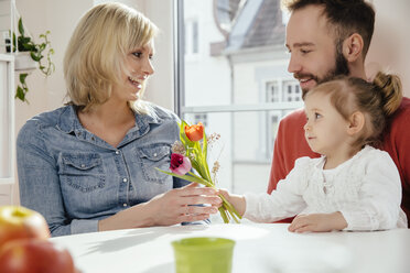 Kleines Mädchen schenkt ihrer Mutter Blumen, während der Vater zusieht - MFF002889