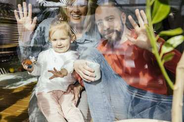 Mother, father and little girl waving out of window - MFF002894