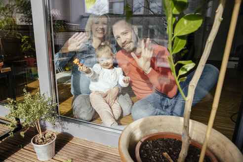 Mother, father and little girl waving out of window - MFF002895