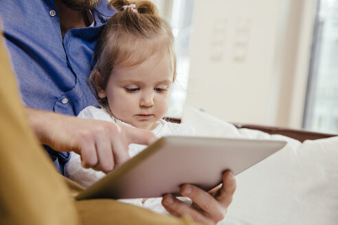 Vater zeigt kleiner Tochter etwas auf digitalem Tablet - MFF002900