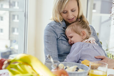 Kleines Mädchen weint in den Armen der Mutter am Frühstückstisch - MFF002909