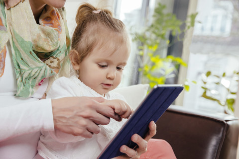 Mother helping daughter using a digital tablet stock photo
