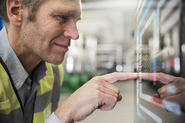 Man using touchscreen device in industrial plant - FKF001725