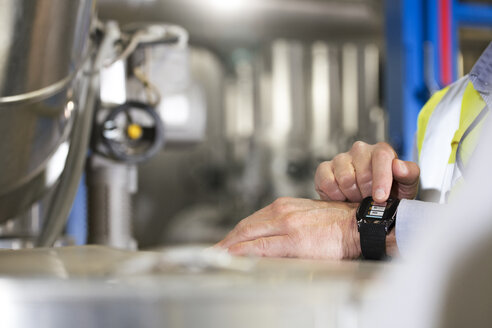 Mann benutzt Smartwatch in Industrieanlage - FKF001730