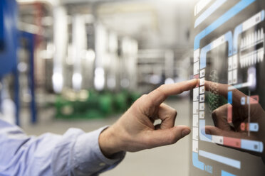 Man using touchscreen device in industrial plant - FKF001734