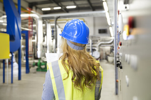 Frau mit Warnweste bei der Kontrolle einer Industrieanlage - FKF001738