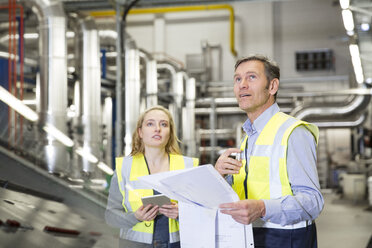 Kollegen mit reflektierendem Halteplan in einer Industrieanlage - FKF001749