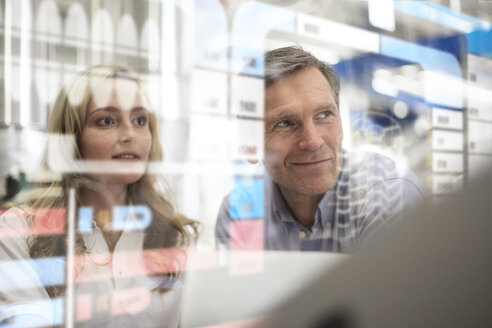 Man and woman looking at transparent touchscreen device - FKF001756