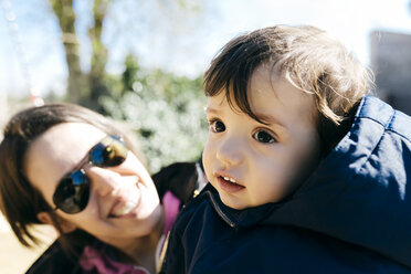 Porträt eines kleinen Jungen mit seiner Mutter im Hintergrund, die ihn beobachtet - GEMF000797