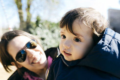 Porträt eines kleinen Jungen mit seiner Mutter im Hintergrund, die ihn beobachtet - GEMF000797