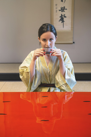 Porträt einer Frau im Yukata, die in einem traditionellen japanischen Zimmer Tee trinkt, lizenzfreies Stockfoto
