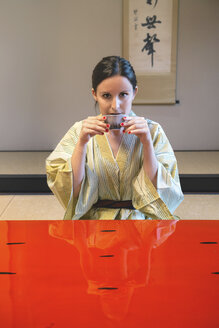 Porträt einer Frau im Yukata, die in einem traditionellen japanischen Zimmer Tee trinkt - GEMF000804