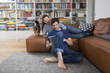Erwachsenes Paar auf dem Sofa liegend, mit digitalem Tablet - FMKF002532