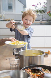 Proud little boy serving pasta in kitchen - FMKF002535