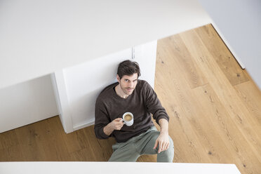 Man sitting on floor drinking coffee - FMKF002540