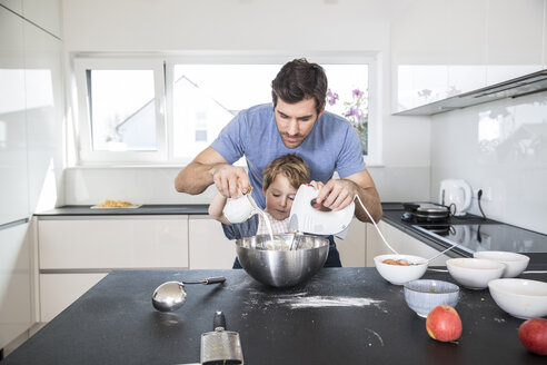 Vater und Sohn bereiten in der Küche Waffelteig vor - FMKF002547