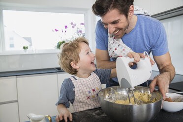 Father and son preparing waffle dough in kitchen - FMKF002548
