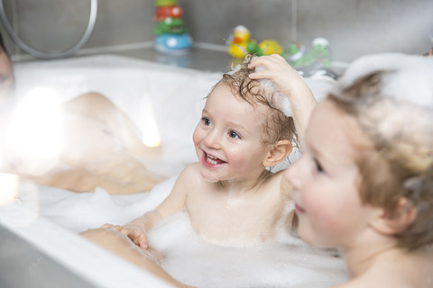 Kleiner Junge hat Spaß in der Badewanne mit Bruder und Vater, lizenzfreies Stockfoto