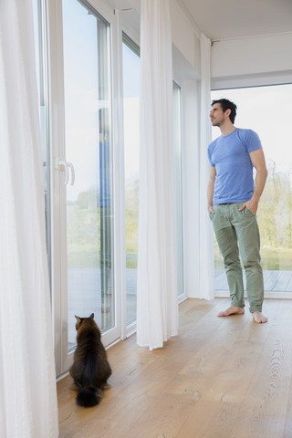 Mann zu Hause, der am Fenster steht und hinausschaut, lizenzfreies Stockfoto