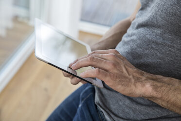 Man at home using digital tablet - FMKF002573