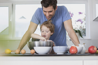 Father and son preparing waffle dough in kitchen - FMKF002596