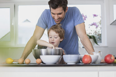 Vater und Sohn bereiten in der Küche Waffelteig vor - FMKF002596