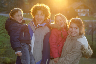 Gruppenbild von vier glücklichen Kindern und Jugendlichen bei Gegenlicht - LBF001421