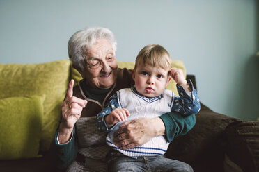 Old woman and her great-grandson sitting on the couch - RAEF000959