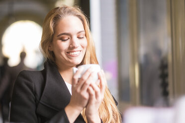 Porträt einer glücklichen blonden Frau mit einer Tasse Kaffee - SIPF000261