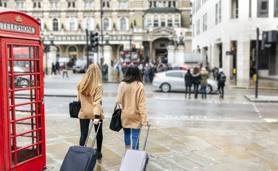 UK, London, Two friends exploring the city, arriving with trolley bags - MGO001564