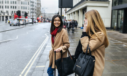 UK, London, Two friends exploring the city, using smart phone - MGOF001566