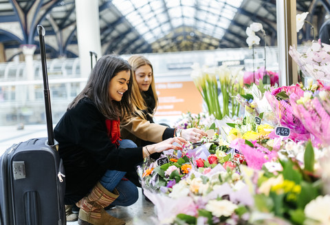 UK, London, Zwei junge Frauen bewundern Blumen am Bahnhof, lizenzfreies Stockfoto