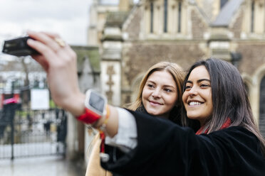 UK, London, Two friends exploring the city, photographing selves in front of Southwark Cathedral - MGOF001577