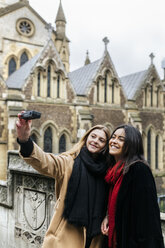 UK, London, Two friends exploring the city, photographing selves in front of Southwark Cathedral - MGOF001578