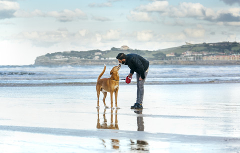 Spanien, Gijon, Mann mit seinem Hund am Strand, lizenzfreies Stockfoto