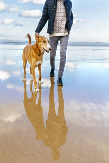 Mann, der mit seinem Hund am Strand spazieren geht - MGOF001602