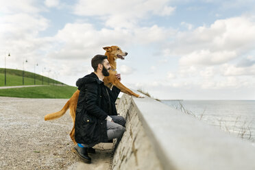 Mann und sein Hund schauen auf das Meer - MGOF001605
