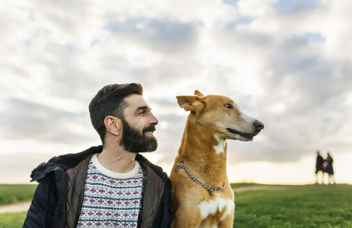 Porträt eines Bärtigen und seines Hundes auf einer Wiese - MGOF001610