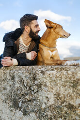 Man and his dog lying side by side on a wall - MGOF001616