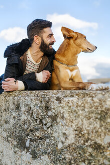 Mann und sein Hund liegen nebeneinander an einer Wand - MGOF001616