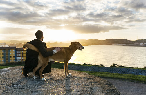 Spain, Gijon, man and his dog at evening twilight - MGOF001620