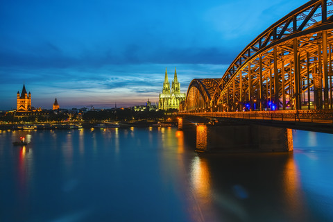 Germany, Cologne, view to lighted Cologne Cathedral with Hohenzollern Bridge in the foreground stock photo