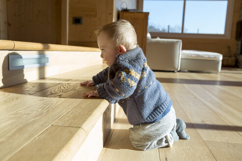 Kleiner Junge hockt auf dem Holzboden und betrachtet seinen Schatten - ZOCF000008