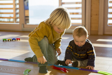 Kleiner Junge und sein Bruder spielen mit Spielzeug Zug auf dem Holzboden zu Hause - ZOCF000011