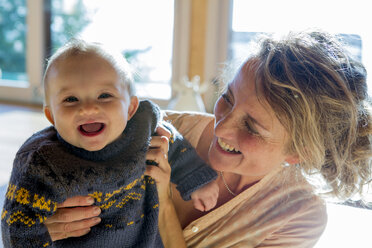 Portrait of laughing baby boy holding by his mother - ZOCF000012