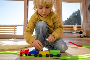 Kleiner Junge spielt mit Spielzeugeisenbahn auf dem Holzboden zu Hause - ZOCF000014