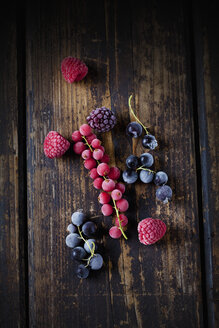 Tiefgefrorene rote und schwarze Johannisbeeren, Himbeeren und Brombeeren auf Holz - CSF027357