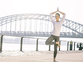 Deutschland, Köln, junge Frau übt Yoga, Baumstellung - MADF000875