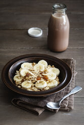 Eine Schale mit Bananen-Haferflocken-Granola und eine Flasche Kakao - EVGF002868